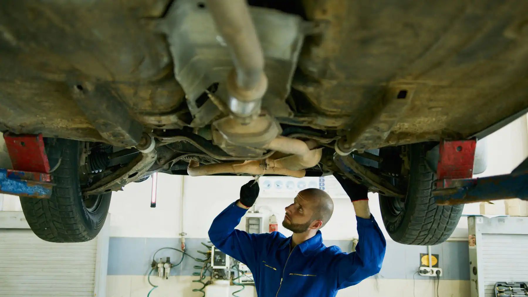 mecânico inspecionando a suspensão por baixo do carro Mecânico inspecionando a suspensão por baixo do carro